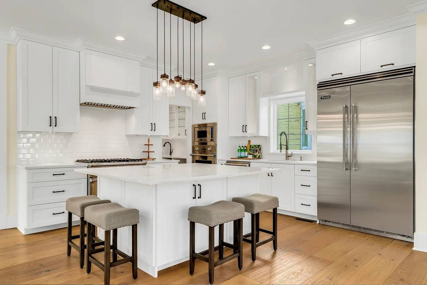 A kitchen with white cabinets and wooden floors.